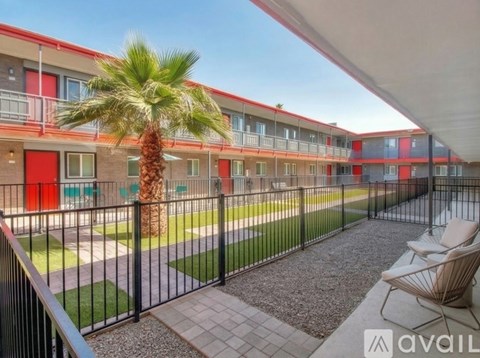A balcony with chairs and a palm tree in front of apartment buildings.