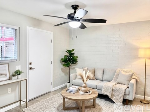 A bedroom with a large bed, a ceiling fan, and a window with blinds.