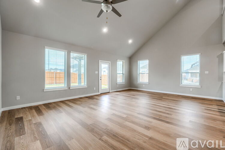 A spacious room with wooden flooring and a ceiling fan.