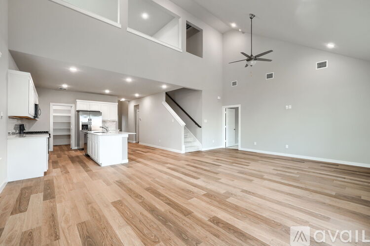 A spacious living room with wooden flooring and a ceiling fan.