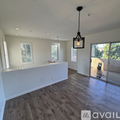 A spacious room with wooden flooring and a hanging light fixture.