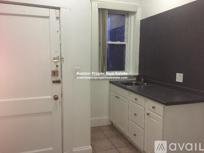 A kitchen with white cabinets and a black countertop.