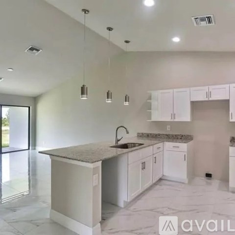 A kitchen with white cabinets and a marble countertop.