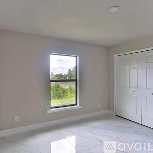 A room with a large window and a white door.