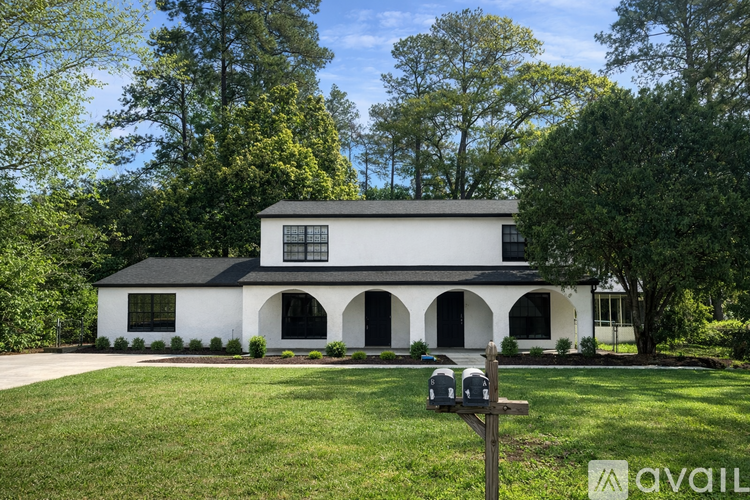A white house with black roof and a mailbox in front.