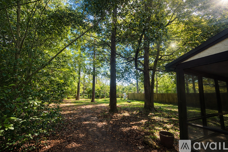 A path in a wooded area with a house on the right.