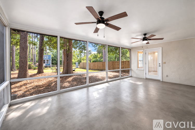 A spacious room with a ceiling fan and sliding glass doors leading to a backyard.