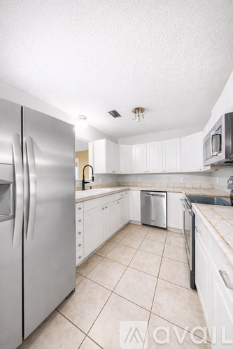 A kitchen with white cabinets and a stainless steel refrigerator.