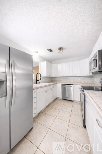 A kitchen with white cabinets and a stainless steel refrigerator.