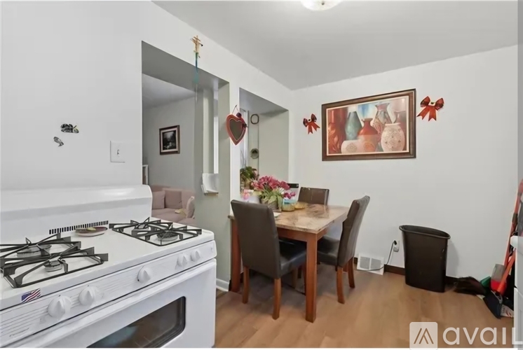 A kitchen with a white gas stove and a dining table with chairs.