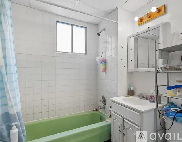 A bathroom with a green tub and white sink.