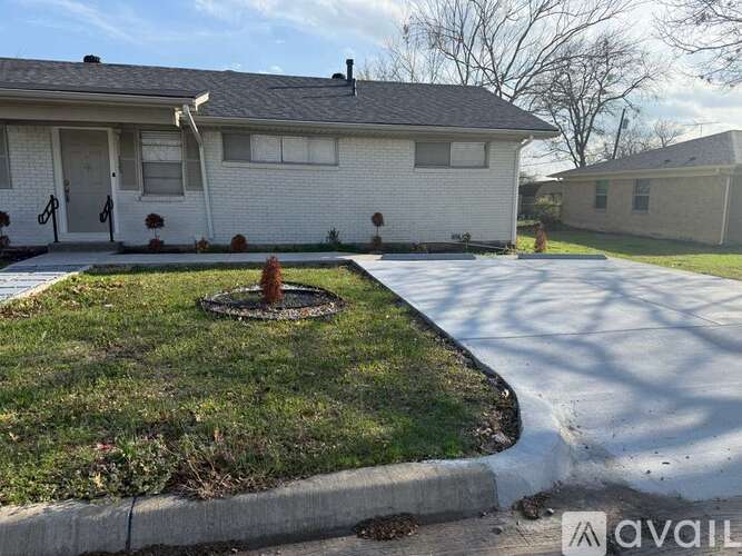 A white house with a grey roof and a small front yard with a fire hydrant.