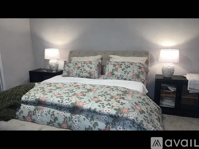 A bed with floral bedding and two lamps on side tables.