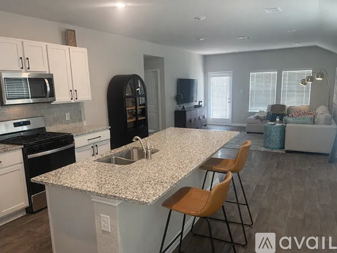A kitchen with granite countertops and a dining area with chairs.