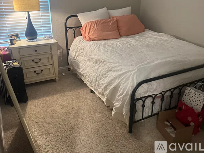 A bedroom with a white bed and a white dresser with a lamp on top.