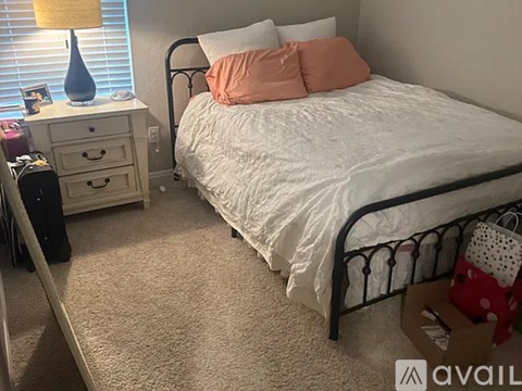 A bedroom with a white bed and a white dresser with a lamp on top.