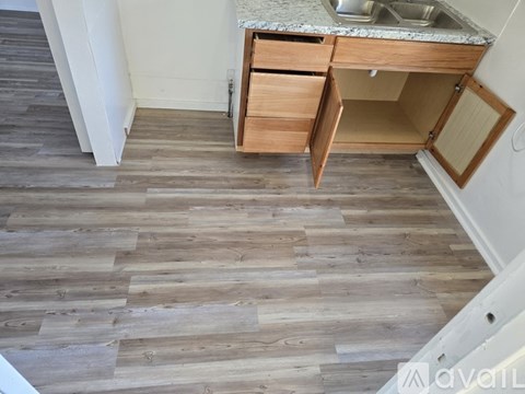 A kitchen with a sink and wooden flooring.