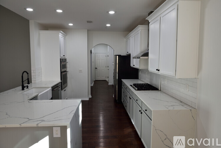 A kitchen with white cabinets and marble countertops.