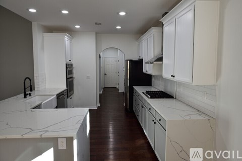A kitchen with white cabinets and marble countertops.