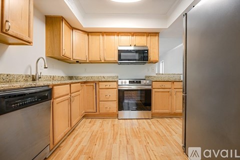A kitchen with wooden cabinets and a stainless steel refrigerator.