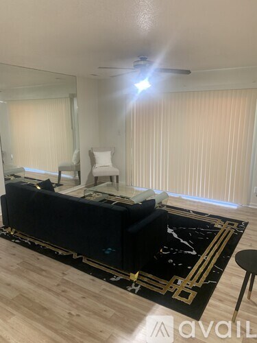 A living room with a black sofa and a black and gold rug.