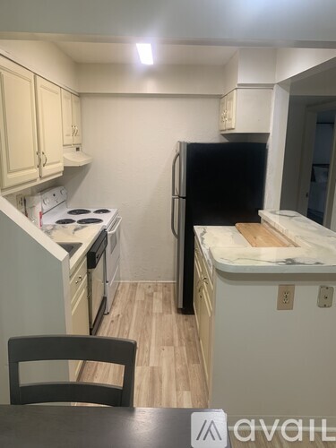 A kitchen with a black refrigerator and white cabinets.