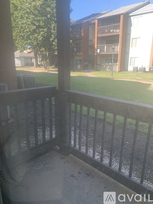 A balcony with a black railing overlooks a grassy area and apartment buildings.