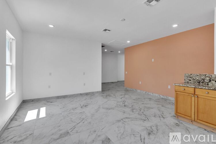 A spacious room with marble flooring and a kitchenette.
