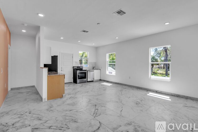A spacious living room with marble flooring and a kitchen area in the background.