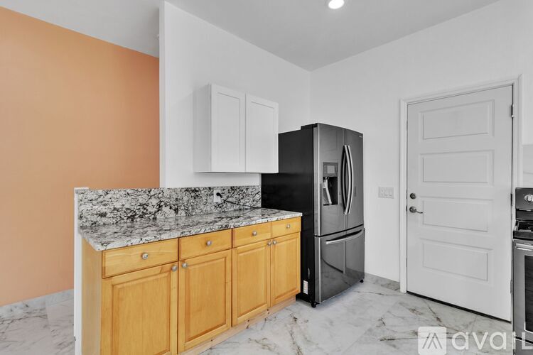 A kitchen with wooden cabinets and a black fridge.