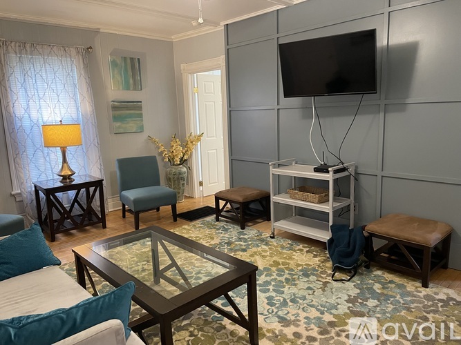 A living room with a glass coffee table and a flat screen TV mounted on the wall.