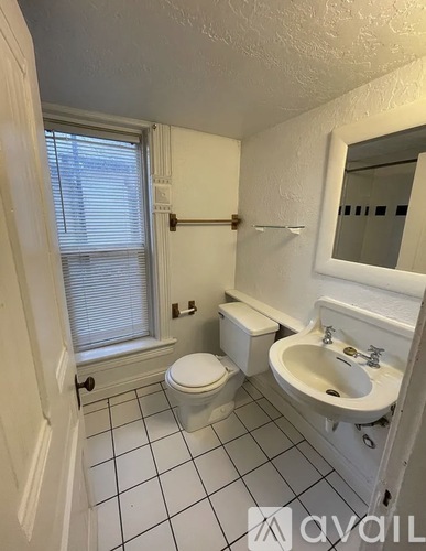 A bathroom with a toilet, sink, and mirror.