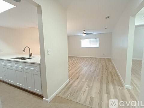 A kitchen with white cabinets and a wooden floor.