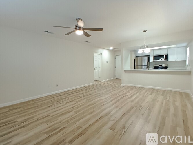A spacious room with wooden flooring and a ceiling fan.