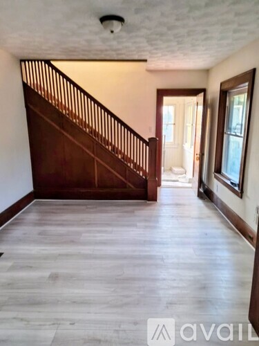 A spacious room with a wooden staircase and light wood flooring.