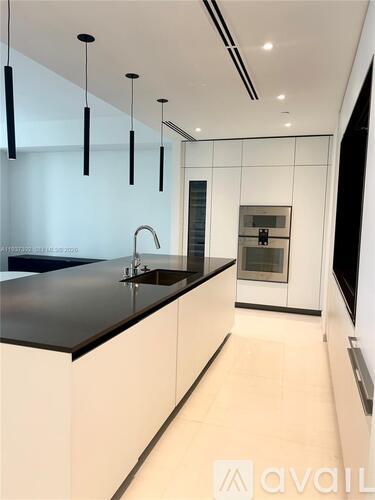 A modern kitchen with a black countertop and white cabinets.