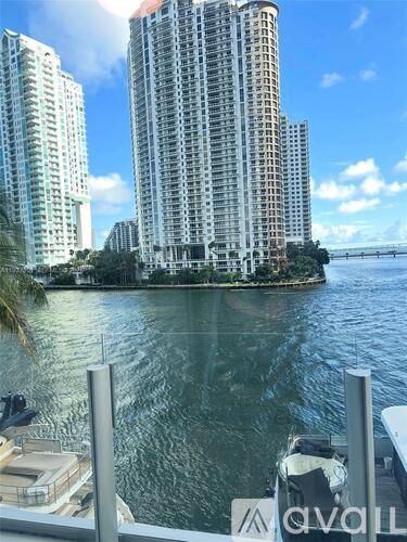 A view of a cityscape with tall buildings and a body of water in the foreground.