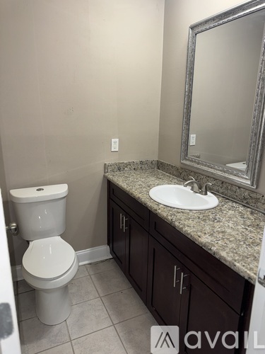 A bathroom with a toilet, sink, and mirror.