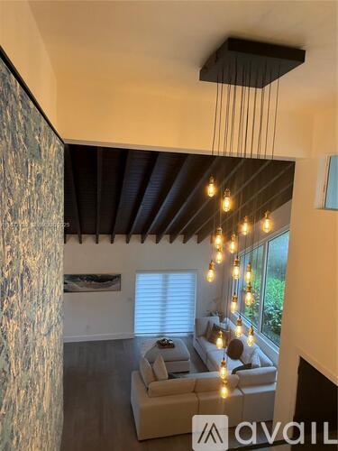 A living room with a couch and a hanging light fixture.