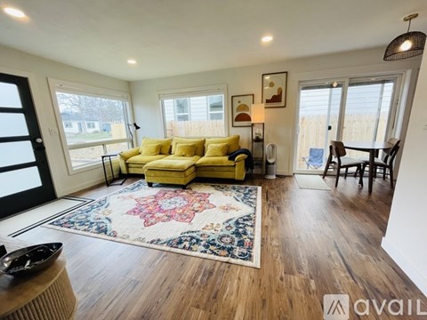 A living room with a yellow couch and a rug on the floor.