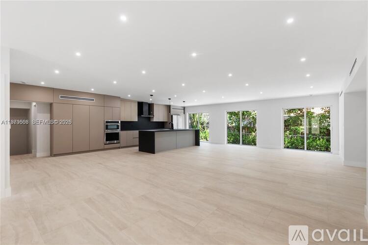 A spacious room with wooden flooring and a kitchen area with a counter and cabinets.