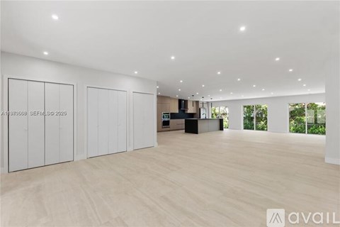 A spacious room with wooden flooring and white walls.
