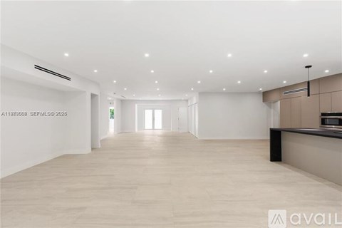 A spacious room with wooden flooring and white walls.