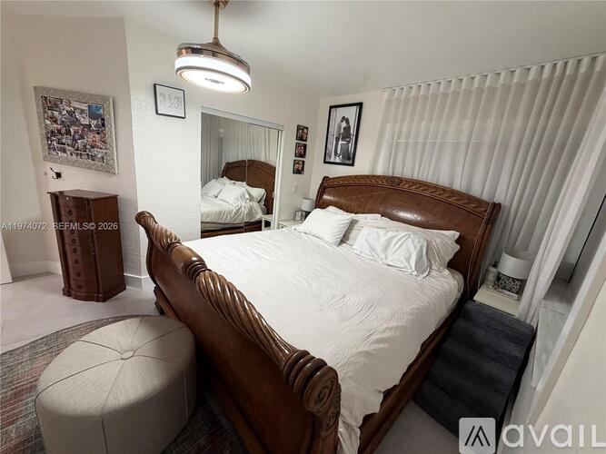 A bedroom with a large bed and a round ottoman.