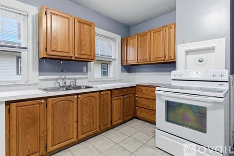 A kitchen with wooden cabinets and a white stove top oven.