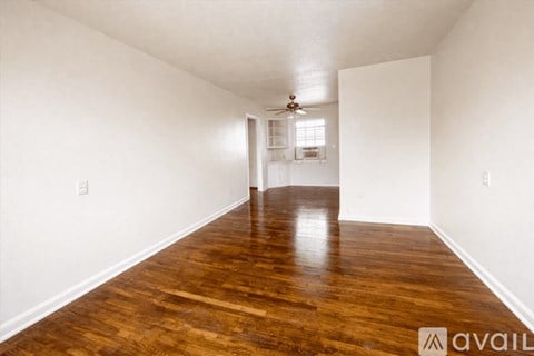 A long hallway with wood floors and a ceiling fan.