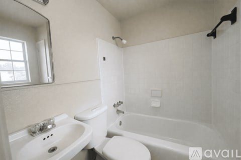 A white bathroom with a toilet, sink, and bathtub.