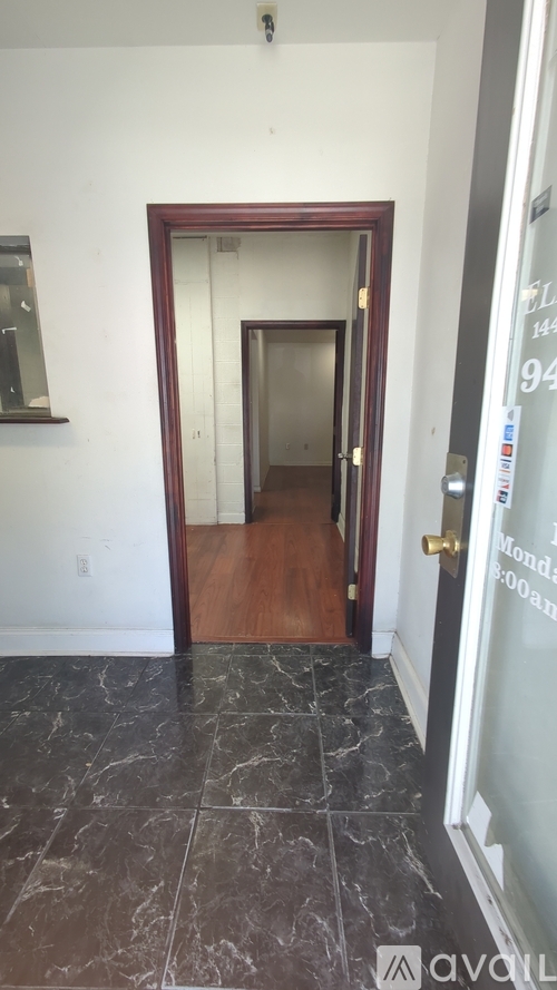 A hallway with a wooden door and a marble floor.