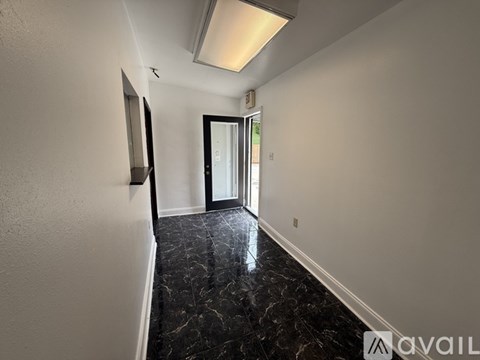 A hallway with a wooden door and a marble floor.