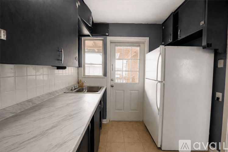 A kitchen with black cabinets and a white refrigerator.